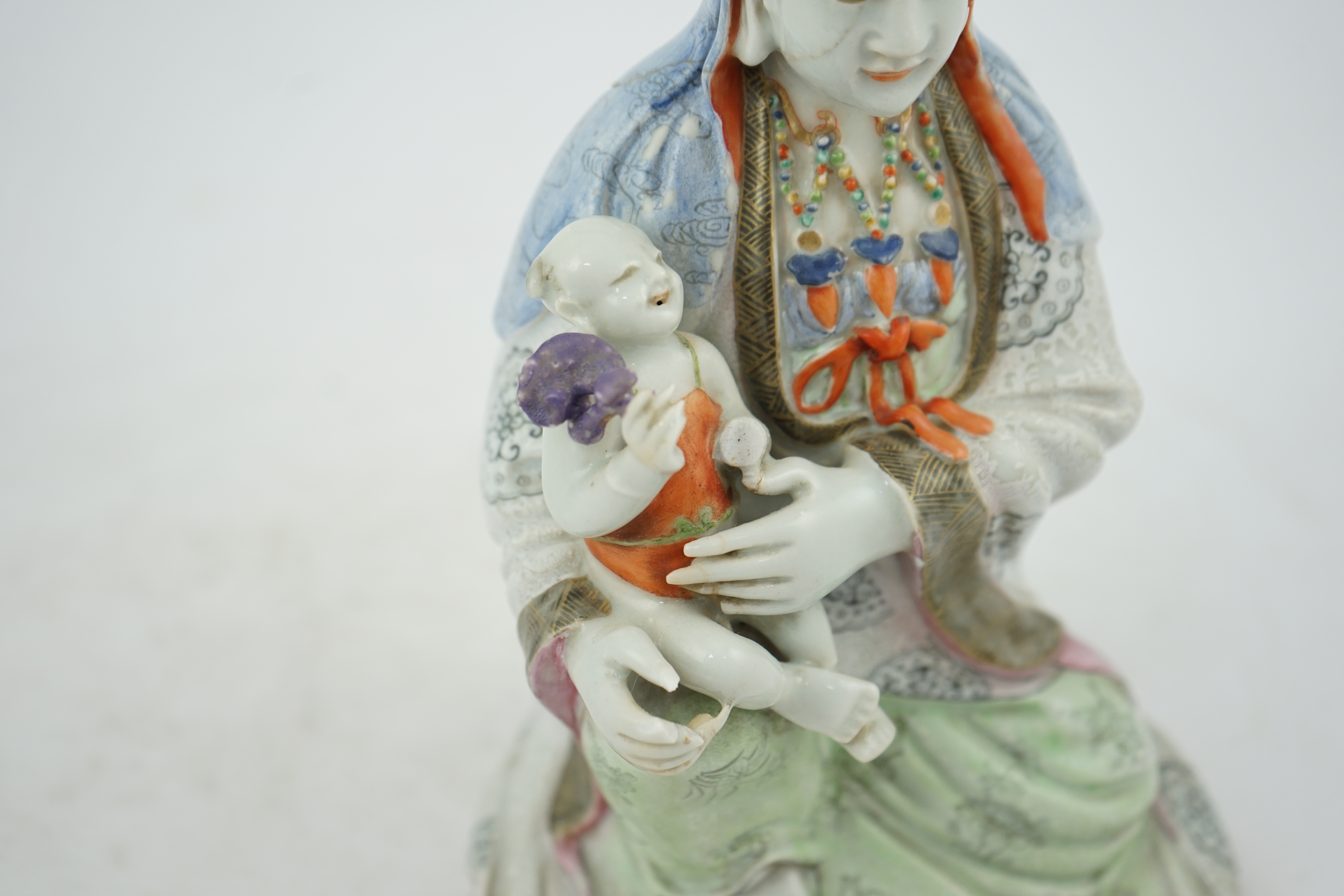 A Chinese enamelled porcelain group of Guanyin holding a child, Qianlong period